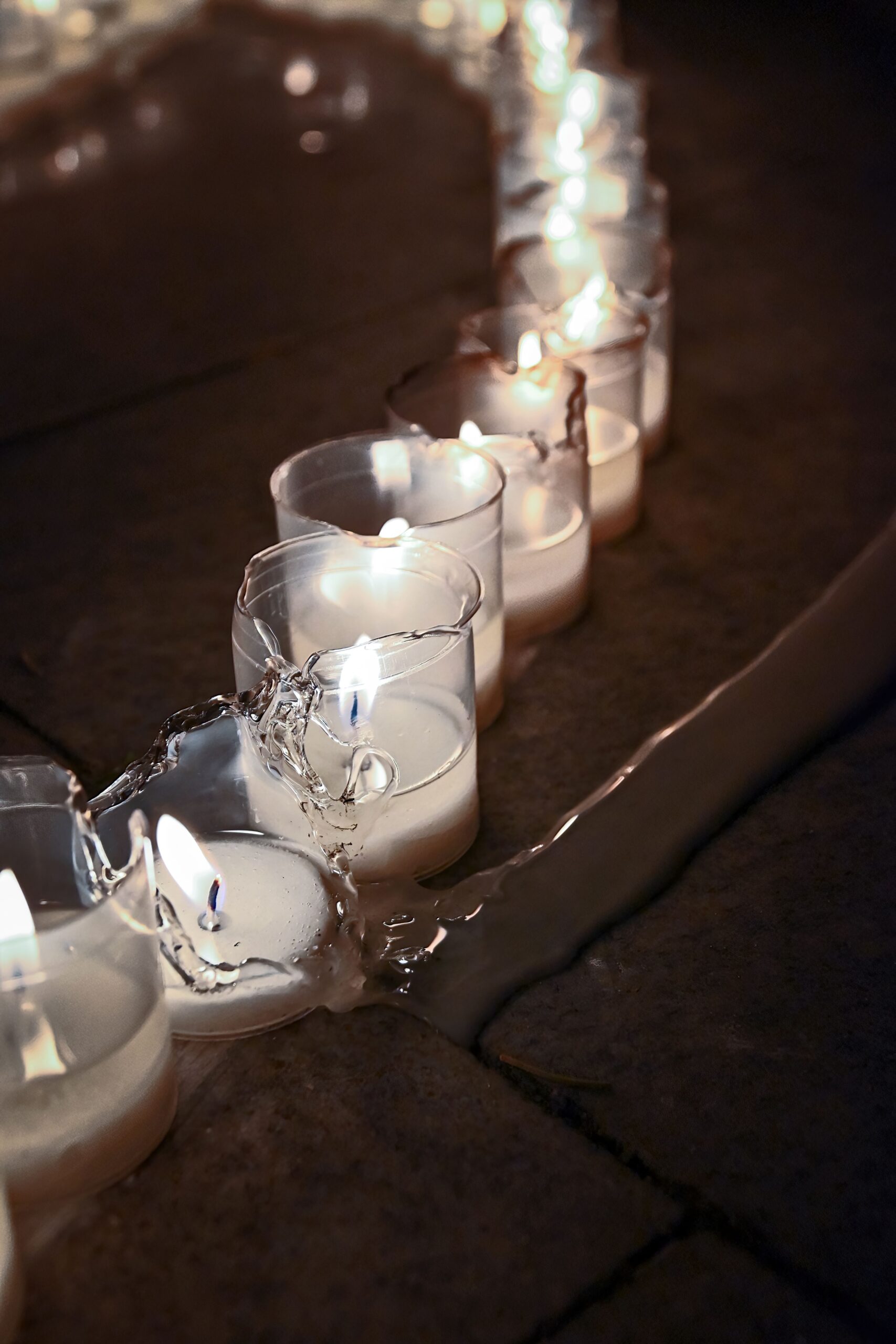 A line of lit votive candles, one is broken